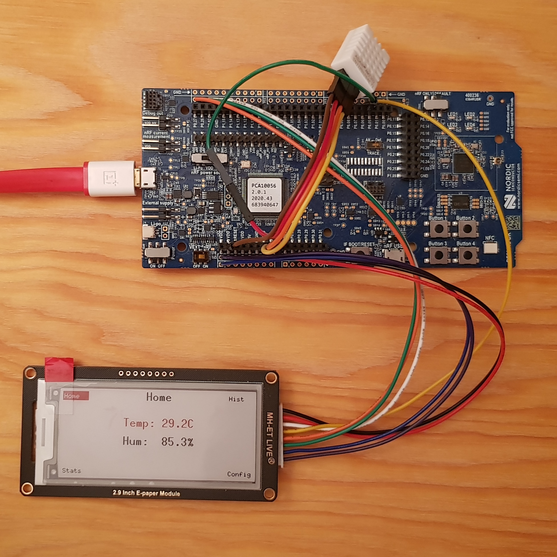 Image of the nRF52840-DK board with the ePaper display connected, displaying the home page with temperature and humidity